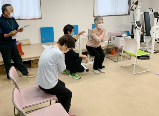 トレーナーの指導でスクワットをする会員